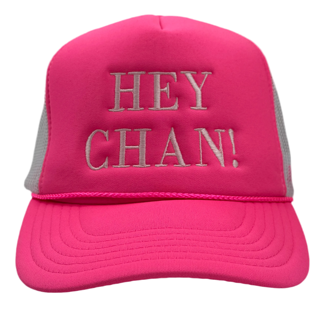 A bright pink trucker hat with gray mesh side panels and silver-gray embroidered text reading 'HEY CHAN!' on the front, shown against a plain white background.