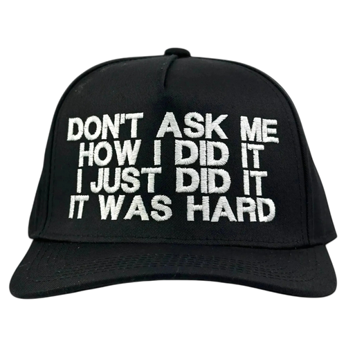A black baseball cap with white embroidered text on the front that reads 'DON'T ASK ME HOW I DID IT I JUST DID IT IT WAS HARD', shown against a solid black background.